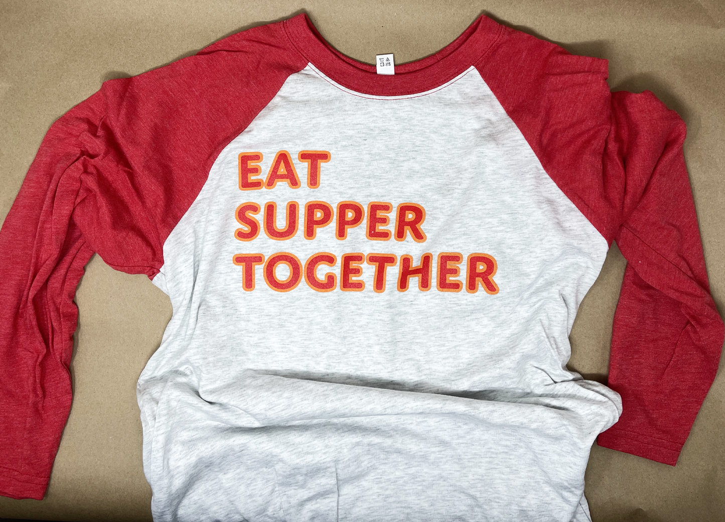Soft, comfortable red and gray baseball jersey style T shirt with 3/4 length sleeves. Text on front reads "EAT SUPPER TOGETHER"