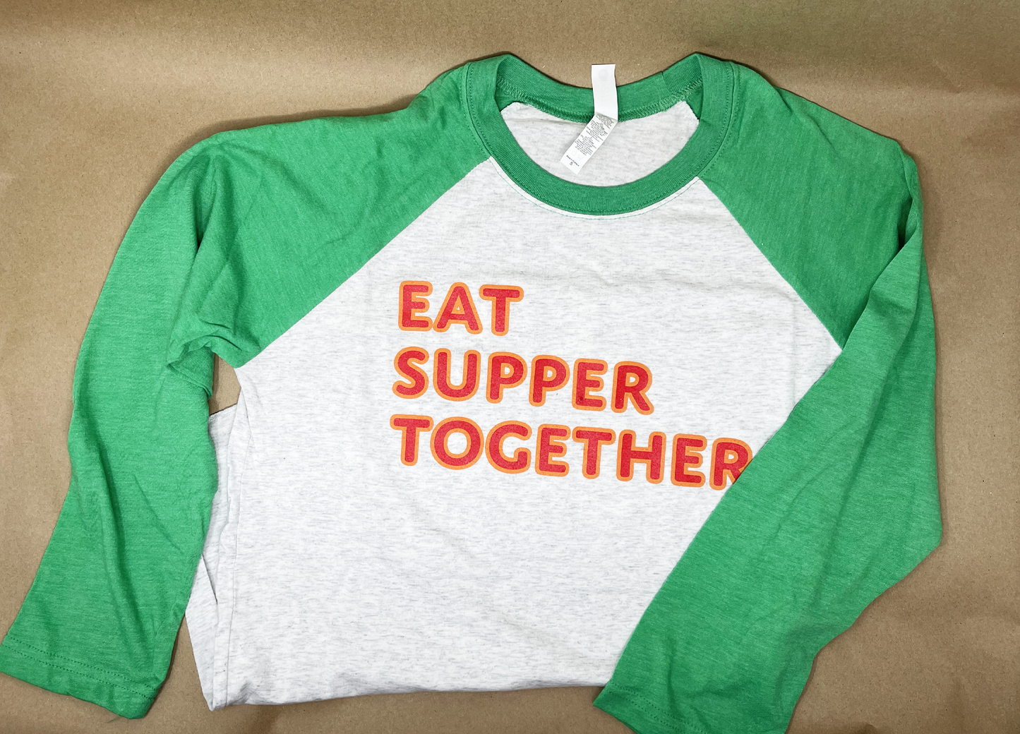 Soft, comfortable gray and green baseball jersey style T shirt with 3/4 length sleeves. Text on front reads "EAT SUPPER TOGETHER"